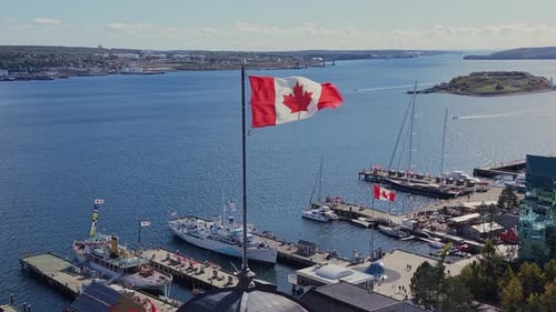 CINEMATIC AERIAL VIEW CANADIAN FLAG WAVING OVER HALIFAX BUILDINGS AND WATERFRONT