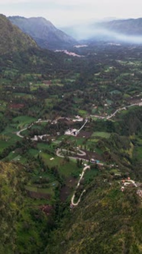 Vertical Drone View of Agricultural Valley with Terraced Farmland Winding Road and Steep Ridges