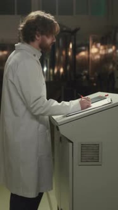 Brewery Supervisor Taking Notes while Inspecting Equipment