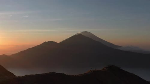 Tourist standing on mount Batur ridge during magical morning sunrise in Bali, aerial