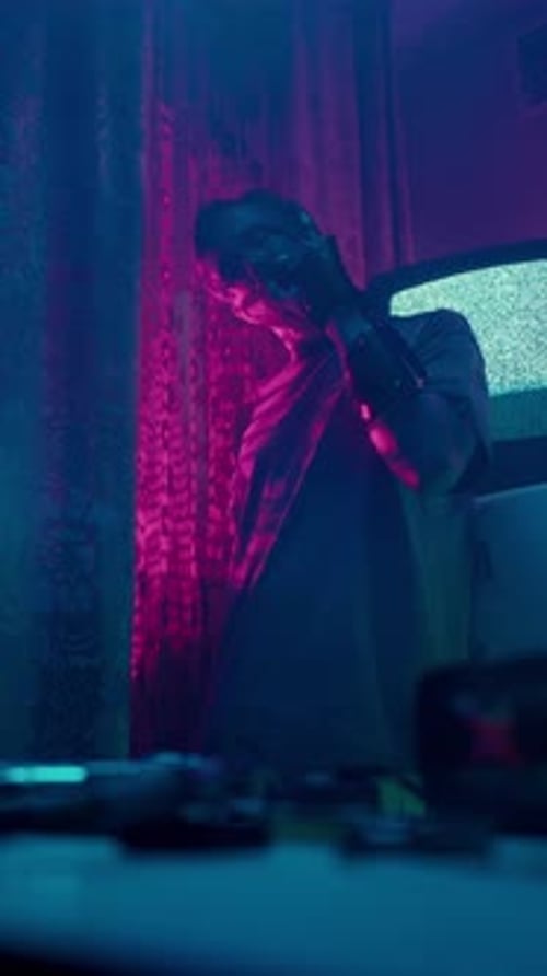 Man Holding Game Controller in Neon Lit Room