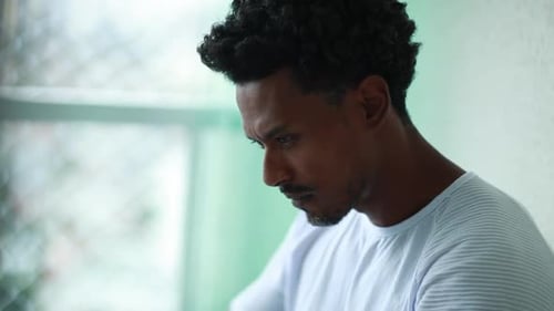 Pensive Man Typing on Laptop by Window