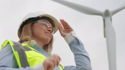 Woman Engineer Wearing Safety Gear by Wind Turbine