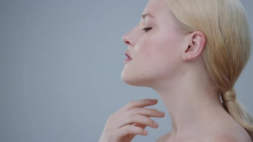 Woman Gently Caresses Neck in Close Up Studio Shot