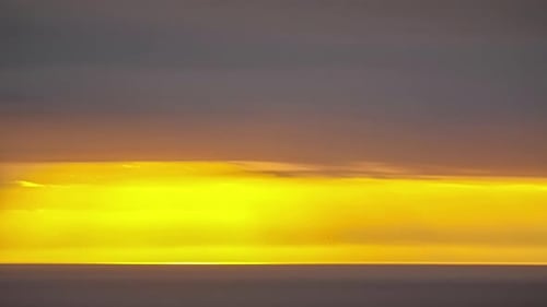 Timelapse of sunset behind the clouds over the sea. Amazing golden light of cloudscape sky and cloud