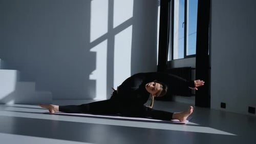 Young Slender Woman Doing Stretching Exercises In Fitness Studio Sitting On Floor In Split Position