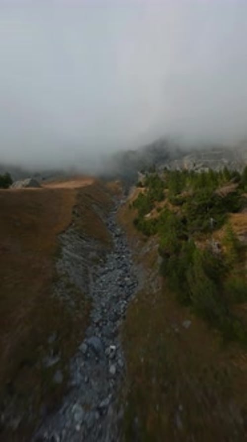 Drone Flight Over Rocky Mountain Ridge in Clouds