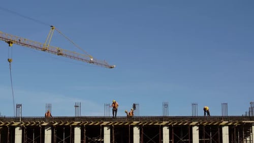 Turmdrehkran verlässt die letzte Ebene der Baustelle, Arbeiter arbeiten an Stahlträgern, die g verbinden