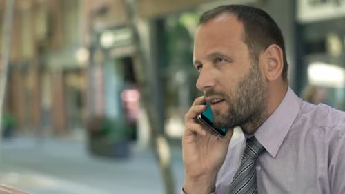 Young Businessman with Laptop Talking on Cellphone Sitting in Cafe 30s