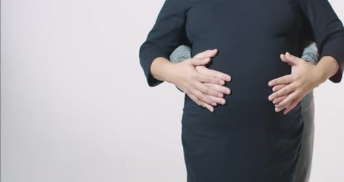 Couples en gros plan massant les mains d'une femme enceinte de 9 mois à terme, ventre isolé, fond blanc