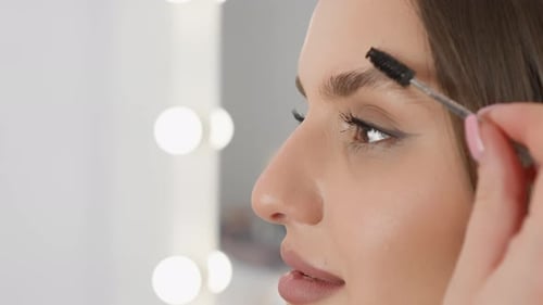 A Woman is Delicately Applying Eyebrow Makeup Using a Brush in a Closeup Shot Focusing on Beauty and