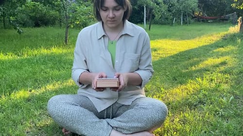 Woman Plays Small Musical Instrument Outdoor at Sunrise
