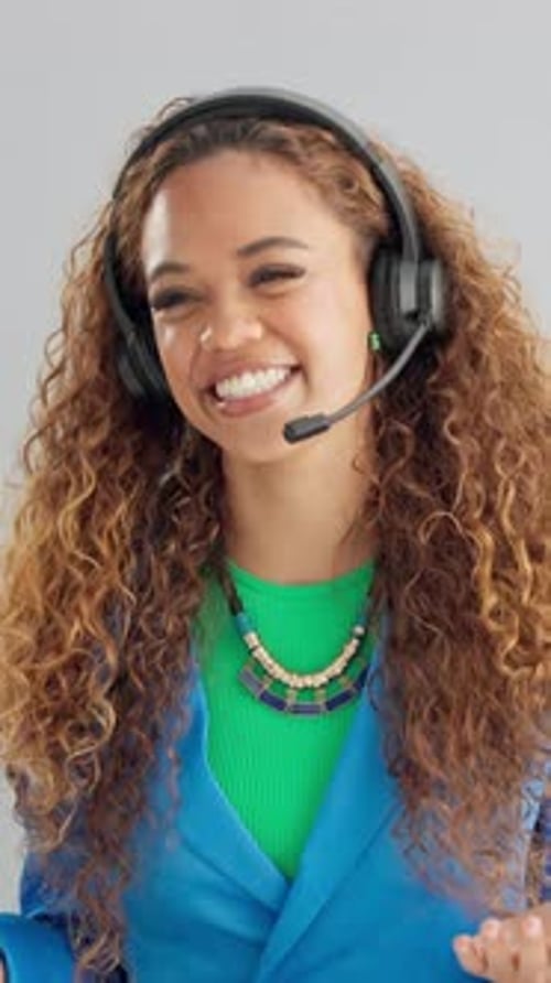 Woman, headset and happy in studio for call center job, contact and tech support by gray background