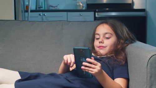 Girl Using Smartphone Reclining on Couch Indoors