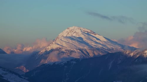 Marvel at the breathtaking sunrise over a snow-covered mountain range silhouette from this stunning