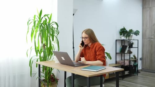 Woman Working on Laptop While Talking on Phone