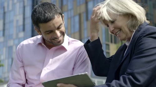 Business colleagues collaborate using a tablet outdoors, daytime