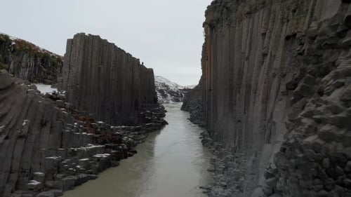 Drone flying through Studlagil canyon in Iceland during a cloudy day