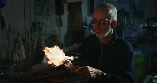 Zeitlupe eines erfahrenen Glasbläsers, der mit Flammen an einem handgefertigten Kunststück aus Glas von p