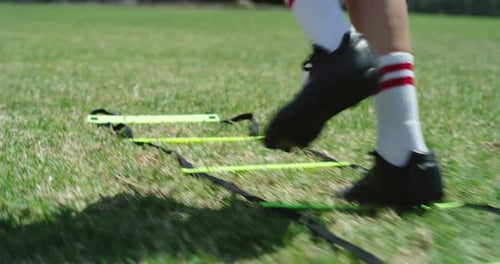 Soccer Player Training with Ladder on Green Field