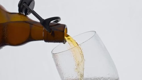 Golden lager beer pouring from brown bottle in super slow motion