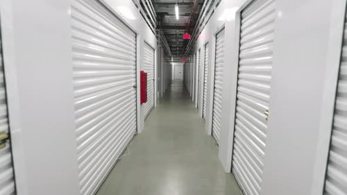 Caméra passant devant des portes à volets roulants en métal blanc dans une unité de rangement en libre-service moderne