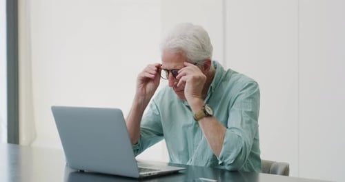 Senior Man Typing on Laptop in Home Office