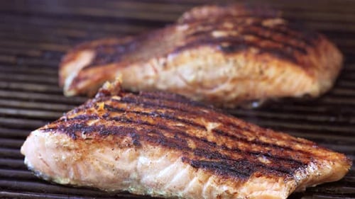 Seasoned and grilled salmon steaks on the barbecue done and ready to serve - slow zoom close up isol
