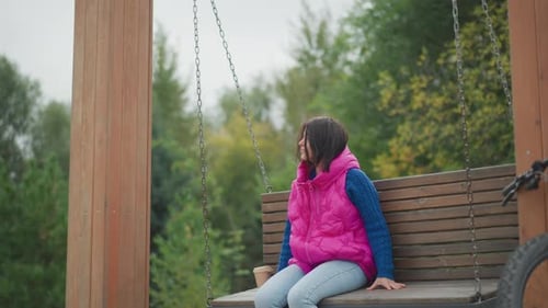 Woman relaxing on wooden swing in park