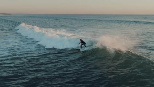 Surfer Riding Wave at Sunrise