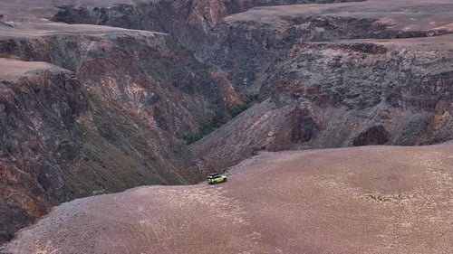 Grünes Geländefahrzeug, das auf einer Klippe mit Blick auf eine Schlucht geparkt ist