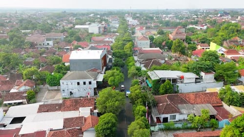 Drohne fliegt durch ein Stadtgebäude mit Straße und Baum in der Mitte