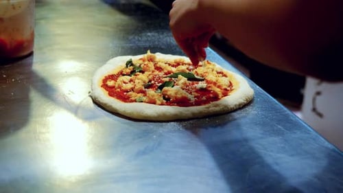 Authentic pizza making process in traditional Italian pizzeria, with the chef adding topings on the