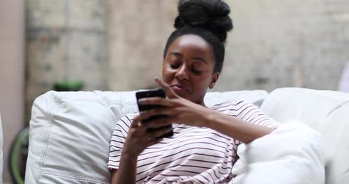 Smiling Woman Using Smartphone Relaxing on Couch