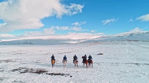 People Riding Horses Across a Snowy Plain