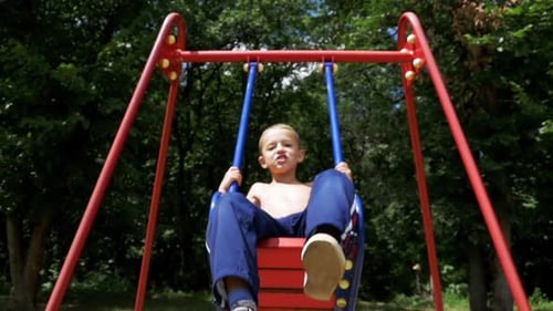 Mother Ride Her Little Son on a Street Swing at Playground in Slow Motion