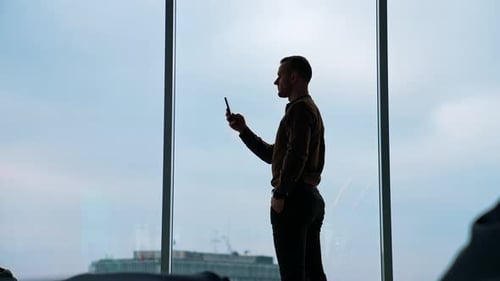 Hübscher Geschäftsmann schreibt im modernen Büro Notizen vom Smartphone