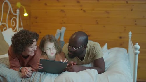 Family Relaxing Together with Tablet on Bed