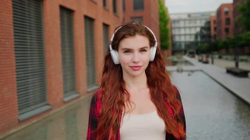 Smiling Woman Listening to Music Via Wireless Headphones on the Street