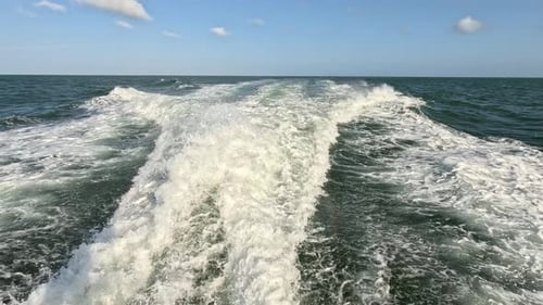 wake of water seen from behind of fast-moving motor boat in a clear sky day, Blue sea, water surface