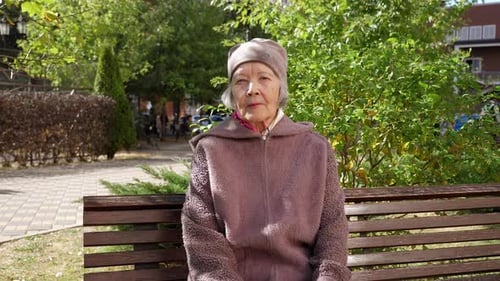 Portrait of an Elderly Grandmother with Gray Hair in a Hat in the Park in Autumn