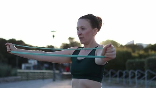 A Woman is Exercising with a Green Resistance Band