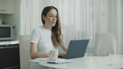 Woman working on laptop at kitchen table