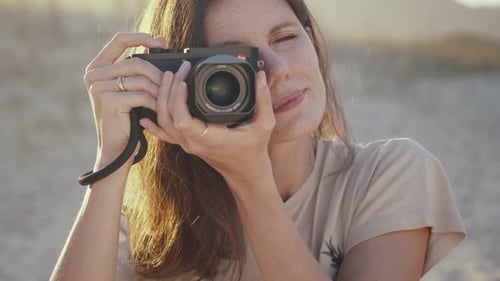 Woman Holding Camera Taking Photographs at Golden Hour