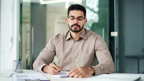 Webcam view. Businessman watching video call online conference taking notes looking at camera