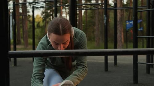 Young Woman Stretching her Hamstrings Before Training in Forest