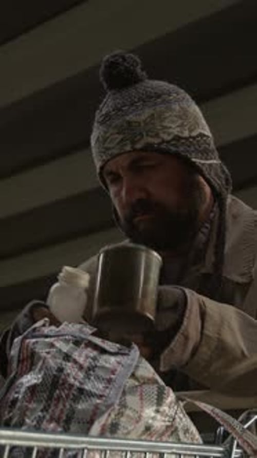 Man under bridge pours liquid from container