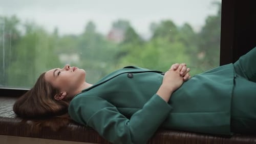 Woman Relaxing in Green Suit by Window