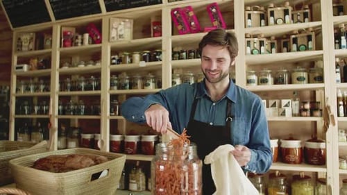 A Young Man Shop Assistant Working in a Zero-Waste Store or Shop