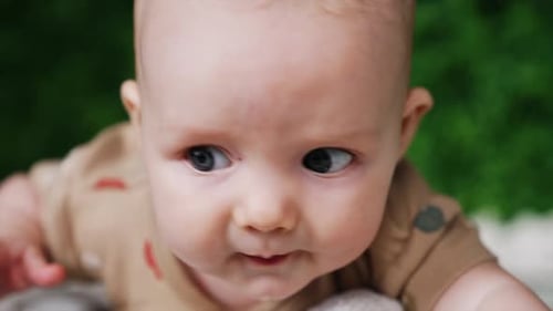 Face of a sweet little Caucasian infant. Close up. Lovely grey-eyed baby looking up with surprise.